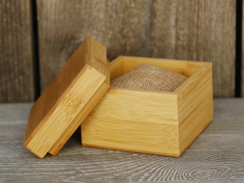 Puede incluir: Una caja de madera natural con tapa, la caja est&aacute; abierta y tiene un forro de tela de arpillera en el interior.