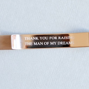 May include: Silver metal tie bar with the inscription "Thank you for raising the man of my dreams".