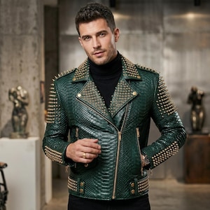 Könnte beinhalten: Eine dunkelgrüne Motorradjacke mit schlangenlederartiger Textur, besetzt mit goldfarbenen Metallnieten an Revers, Schultern und Ärmeln. Die Jacke verfügt über einen diagonalen goldenen Reißverschluss, Reißverschlusstaschen und einen Gürtel.