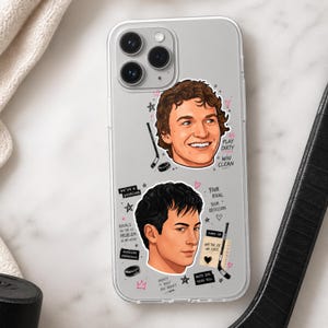 May include: Clear phone case featuring two illustrated faces with hockey-themed graphics. The case includes text such as "Play Dirty, Win Clean", "Your Rival, Your Obsession", and "Hockey is Easy, You Aren't".