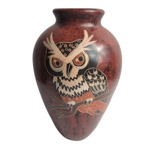 May include: A teardrop-shaped ceramic vase with a mottled dark red and brown finish. The front features a detailed etched illustration of an owl perched on a branch, rendered in shades of cream, black, and orange, with large, expressive eyes.
