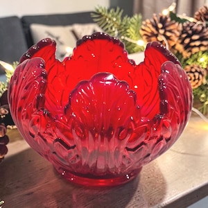 May include: A vibrant red glass bowl with a petal-like design. The bowl has a rounded shape with a wide opening and sits on a small base. The glass is transparent, allowing light to pass through, and is suitable for decorative purposes.
