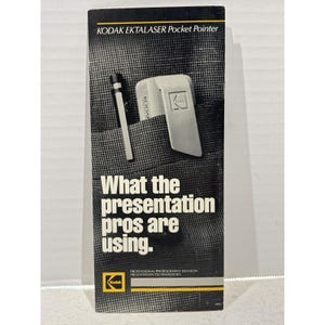 May include: A rectangular product brochure for the Kodak Ektalaser Pocket Pointer. The cover features a black and white image of a pen and a pointer in a pocket, with the text: KODAK EKTALASER Pocket Pointer, What the presentation pros are using.
