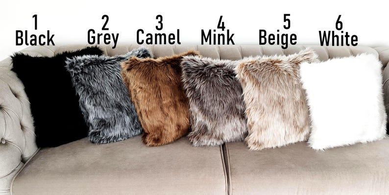 Pu&ograve; includere: Sei cuscini in finta pelliccia in vari colori: nero, grigio, cammello, visone, beige e bianco. I cuscini sono disposti su un divano chiaro. Ogni cuscino &egrave; etichettato con un numero e il nome del colore.