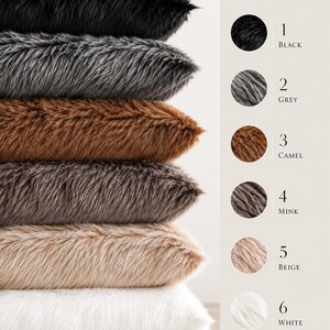 Pu&ograve; includere: Una pila di sei cuscini in finta pelliccia in vari colori: nero, grigio, cammello, visone, beige e bianco. I cuscini fanno parte della "Faux Fur Pillow Collection" e hanno un aspetto morbido e strutturato.