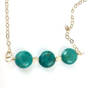 Puede incluir: Un collar turquesa y dorado con tres cuentas redondas de turquesa y dos cuentas de cristal transparente.