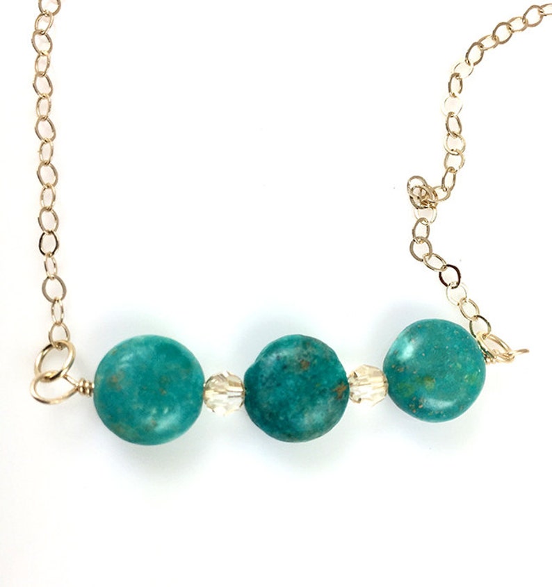 Puede incluir: Un collar turquesa y dorado con tres cuentas redondas de turquesa y dos cuentas de cristal transparente.