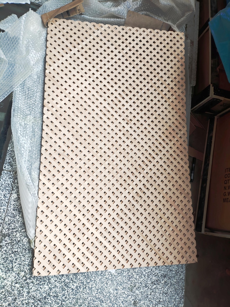 a rectangular piece of wood with a lattice pattern, sitting on a surface with a textured background.