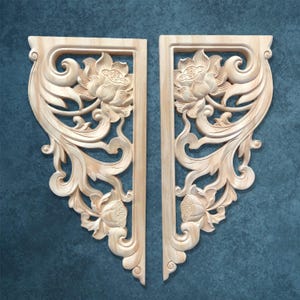 Puede incluir: Dos paneles decorativos de madera sin terminar con intrincadas tallas florales y de hojas. Cada panel presenta un diseño de flor de loto y un marco rectangular. Los paneles están sobre un fondo verde azulado.