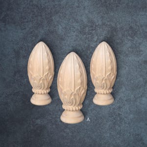 Three ornate wooden finials are arranged in a row against a textured blue background.