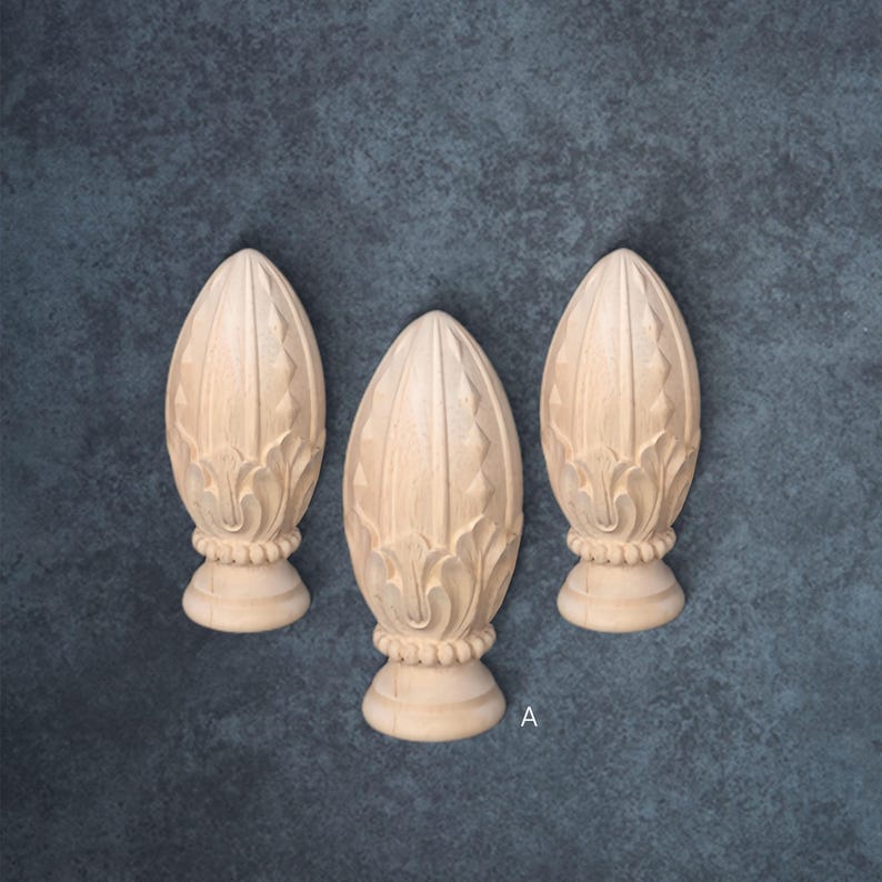 Three ornate wooden finials are arranged in a row against a textured blue background.