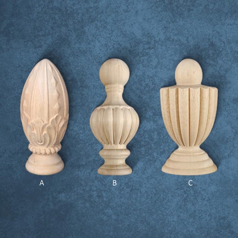 Three wooden finials of different shapes and sizes are displayed against a blue textured background.
