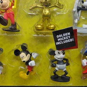May include: A set of Mickey Mouse figurines in various poses, including a golden Mickey. The packaging includes the Disney Mickey logo and the text "THE TRUE ORIGINAL". A tag reads "GOLDEN MICKEY INCLUDED!"
