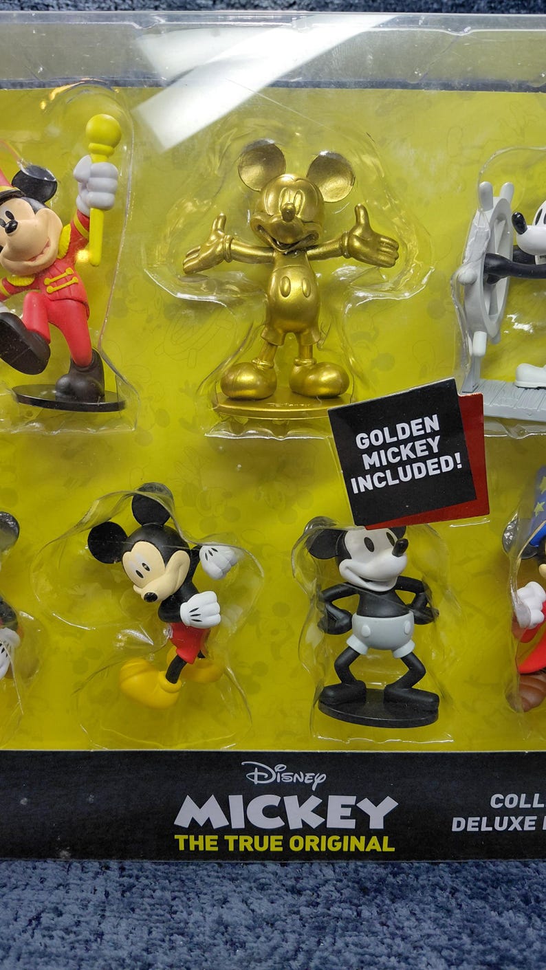 May include: A set of Mickey Mouse figurines in various poses, including a golden Mickey. The packaging includes the Disney Mickey logo and the text "THE TRUE ORIGINAL". A tag reads "GOLDEN MICKEY INCLUDED!"
