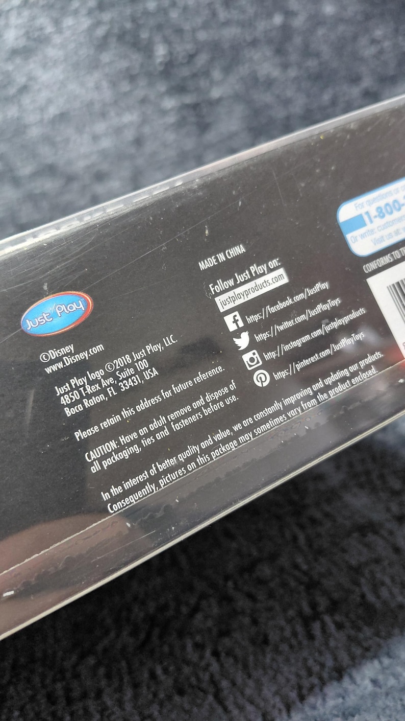 May include: Black product packaging with the Just Play logo and Disney branding. The packaging includes website addresses, social media handles, and a warning about adult supervision. Made in China.
