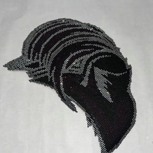 May include: A black beaded applique in the shape of a stylized feather or leaf. The design features a dark background with silver-colored beads outlining the shape and adding texture. The applique is likely for embellishing clothing or accessories.
