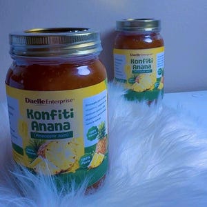 May include: Two glass jars of Daelle Enterprise Konfiti Anana (Pineapple Jam) with metal lids. The labels feature text and images of pineapple slices. The jars are filled with a golden-brown jam, and the labels state "100% Natural" and "100% Pure."