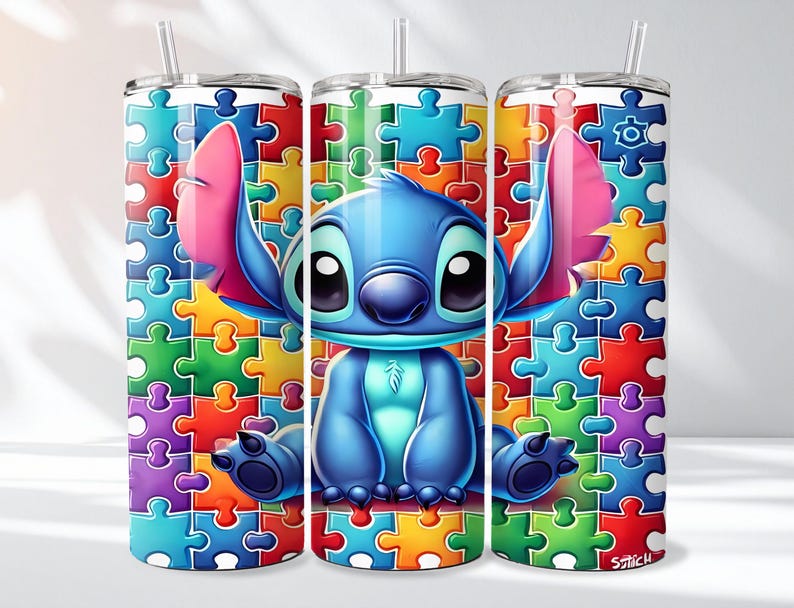 May include: A stainless steel tumbler featuring a colorful puzzle pattern and a cartoon character. The character is blue with large black eyes, pink ears, and is sitting on a puzzle piece background. The tumbler includes a straw.