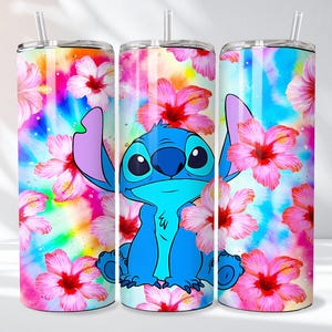 May include: A set of three stainless steel tumblers featuring a vibrant design. The tumblers showcase a blue cartoon character surrounded by pink hibiscus flowers against a colorful, tie-dye background. Each tumbler has a straw.