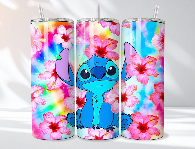May include: A set of three stainless steel tumblers featuring a vibrant design. The tumblers showcase a blue cartoon character surrounded by pink hibiscus flowers against a colorful, tie-dye background. Each tumbler has a straw.