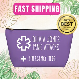 Puede incluir: Una bolsa morada con cremallera con texto y símbolos blancos. El texto dice "OLIVIA JONES PANIC ATTACKS + EMERGENCY MEDS". Un símbolo blanco de la estrella de la vida está a la izquierda. Un sello dorado dice "100% BEST QUALITY".