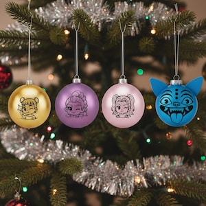 Peut inclure: Quatre boules de Noël suspendues à un sapin décoré. Les boules sont dorées, violettes, roses et bleues. Chaque boule présente un dessin de personnage de dessin animé. L'arbre est décoré de lumières et de guirlandes.
