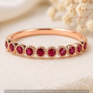 Puede incluir: Anillo de oro rosa con una hilera de gemas rojas brillantes. Las gemas están engastadas en un delicado engaste biselado festoneado, creando una línea continua de color. La banda del anillo es de oro rosa liso y pulido.