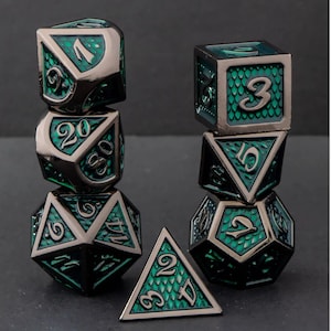 May include: A set of seven metal polyhedral dice in a stacked arrangement. The dice have a dark gunmetal finish with emerald green accents and numbers. The dice include a D4, D6, D8, D10, D12, D20, and a percentile die.