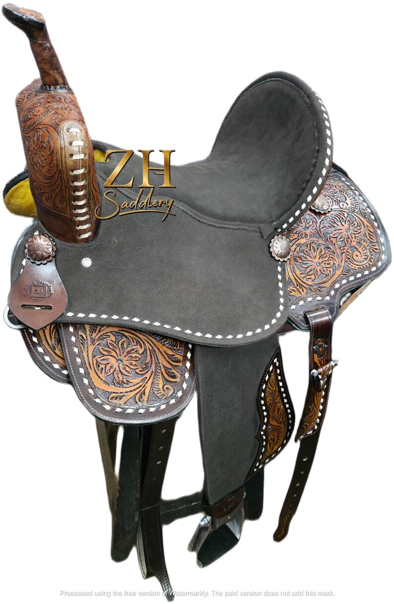May include: A brown and black Western saddle with intricate floral tooling. The saddle features a dark gray seat, decorative silver conchos, and the text "ZH Saddlery". The saddle is designed for horseback riding.