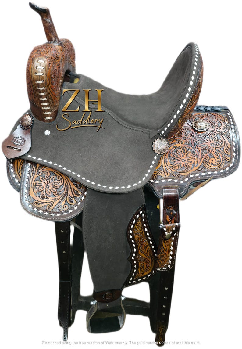 May include: A brown and gray Western saddle with intricate floral tooling. The saddle features a dark gray seat, decorative silver conchos, and the text "ZH Saddlery". The saddle is designed for horseback riding.