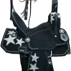 May include: Black western saddle with silver star detailing and white stud accents. Includes a matching bridle, breast collar, and stirrups. The saddle features a suede seat, designed for horseback riding.