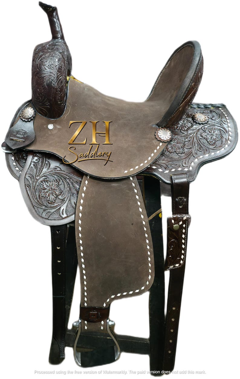 May include: A brown leather western saddle with intricate floral tooling and silver accents. The saddle features a high cantle, a horn, and stirrups. The text "ZH Saddlery" is visible on the saddle.