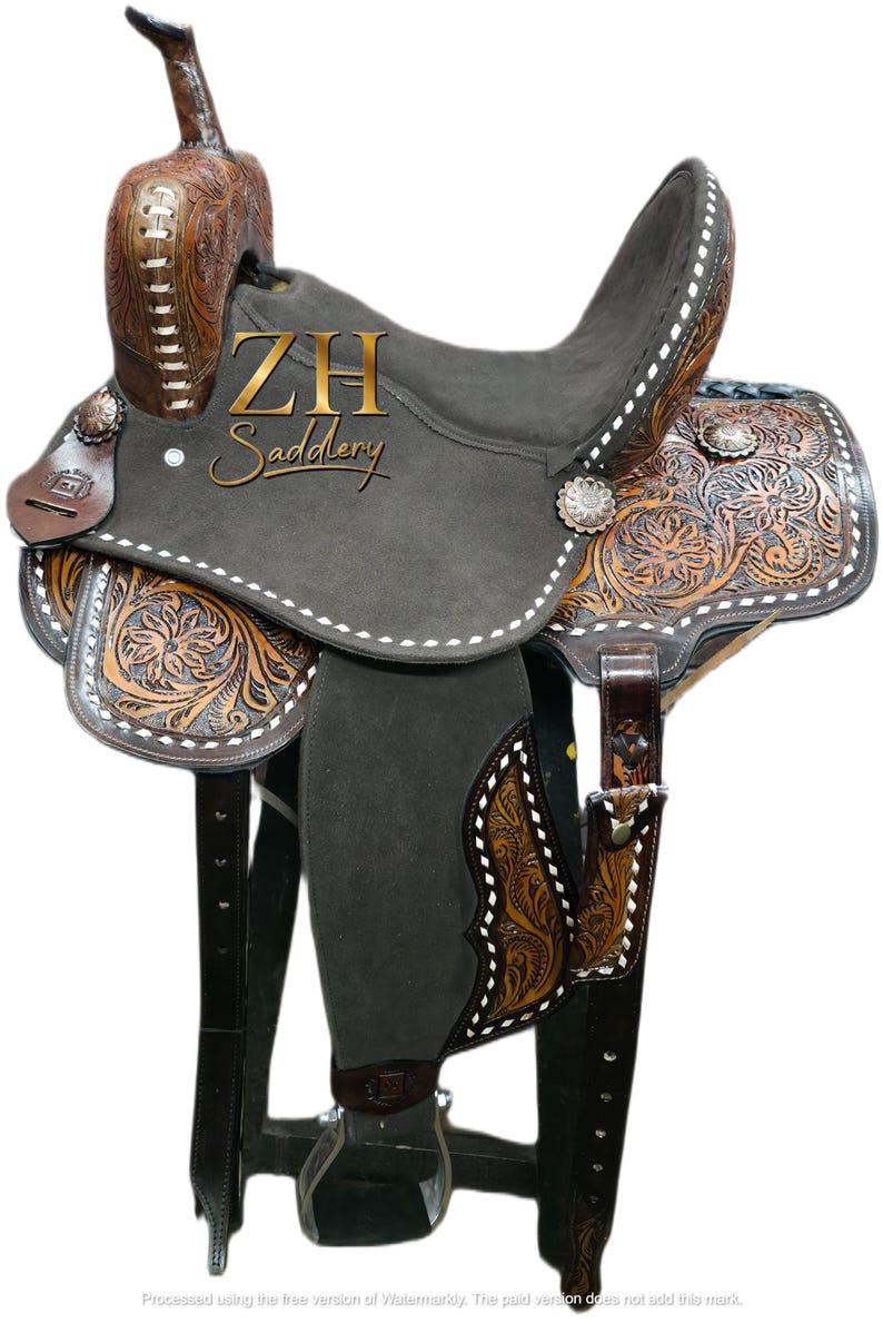 May include: A Western-style saddle with a gray suede seat and intricate floral tooling on the brown leather. The saddle features silver-toned conchos and white stitching. The text "ZH Saddlery" is visible on the saddle.