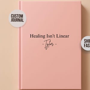 May include: A pink custom journal with the text "Healing Isn't Linear - Tyler" in black script. The journal has a clean, minimalist design. The image also includes a "Custom Journal" and "Ships Fast" sticker.