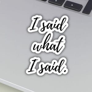 May include: A white sticker with the phrase "I said what I said" in a black, cursive font. The sticker is on a laptop. Two round stickers are also visible, one that says "Custom Sticker" and another that says "Ships Fast."