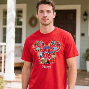 Puede incluir: Camiseta roja con un dise&ntilde;o en forma de Mickey Mouse lleno de coches de dibujos animados. El dise&ntilde;o incluye varias ilustraciones de coches y el nombre "Scott" en letra cursiva. La camiseta es de manga corta.