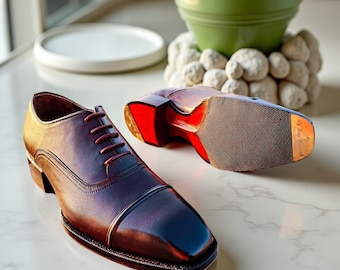 May include: A pair of polished, burgundy leather dress shoes with a square toe and red soles. The shoes have a classic lace-up design and a low heel. One shoe is upright, while the other is flipped over, showcasing the sole's details.