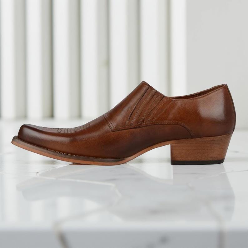 May include: A brown leather shoe with a square toe and a short, stacked heel. The shoe has a slip-on design with a stitched vamp and a subtle decorative pattern on the toe. The heel measures approximately 1.5 inches.