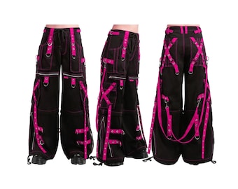 May include: Black cargo pants with bright pink accents. The pants feature multiple pockets, zippers, and straps with metal hardware. The design includes pink stitching and adjustable straps, creating a bold, edgy look. The pants have a drawstring waist.