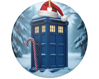 May include: A blue police box ornament with a Santa hat on top and a candy cane. The ornament is round and has a gold string for hanging. The background shows a snowy winter scene with pine trees.