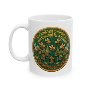 May include: A white ceramic mug featuring a circular graphic with a green background. The design shows cartoon mosquitoes and hiking ticks with the text: The road less traveled is less traveled for a reason: mosquitoes and ticks.