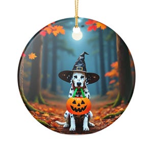 Peut inclure: Ornement rond d'Halloween avec un dalmatien portant un chapeau de sorcière et tenant une citrouille orange. L'arrière-plan montre une forêt avec des feuilles d'automne. L'ornement a une ficelle dorée pour l'accrocher.
