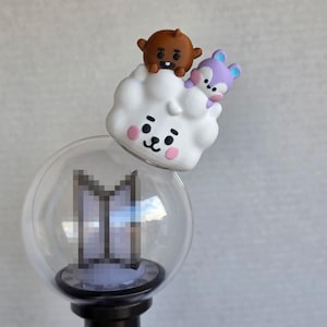 May include: A clear spherical light stick topper featuring a white cloud-shaped character with pink cheeks, a small brown round character, and a tiny purple animal figure perched on top, mounted on a black base with a pixelated logo inside the sphere.