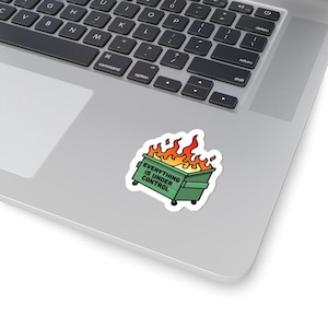 May include: A sticker featuring a green dumpster engulfed in flames. The sticker has the text "EVERYTHING IS UNDER CONTROL" in white. The sticker is placed on a laptop.