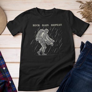 Ruck Rain Repeat T-Shirt, Soldier Under Poncho with Ruck in Stylized Rain, Dual-Color Vector Graphic, Military Stencil Combat Tee