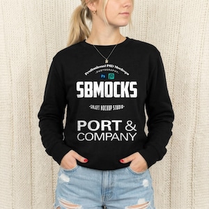 May include: Black long-sleeve sweatshirt with the text "SB MOCKS" in white block letters. Below the text is "-SMART MOCKUP STUDIO-" and "PORT & COMPANY". The top of the sweatshirt has the text "Professional PSD Mockups PHOTOGRAPHY" in a curved design.