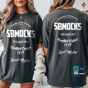 May include: Two charcoal gray t-shirts with white text. The front of the shirt reads "SBMOCKS", "Comfort Colors 1717", and "Smart Mockup". The back of the shirt also has the text "SBMOCKS", "Comfort Colors 1717", and "Smart Mockup". The shirts are part of a professional PSD mockup.