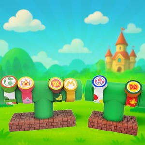 May include: Two green pipe-shaped display stands with colorful wristbands featuring iconic video game characters. The wristbands have various designs, including a Yoshi egg, a crown, and a mushroom. The stands are on brick platforms.