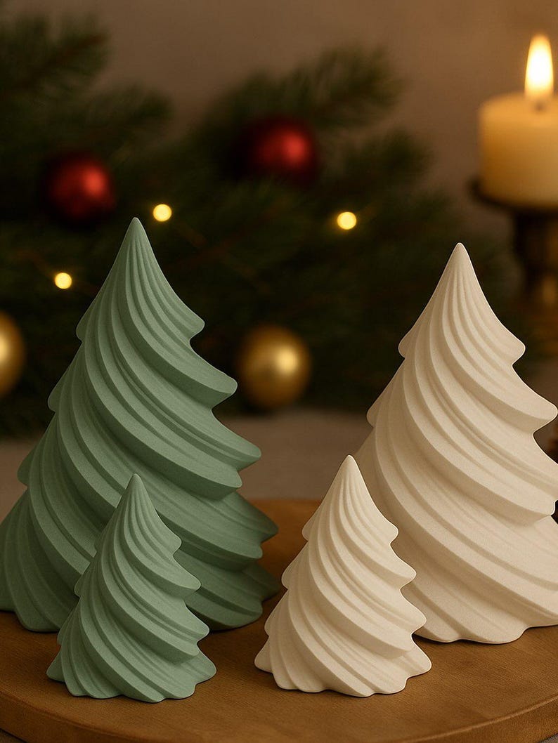 May include: Four decorative Christmas tree figurines in varying sizes. Two are a soft green, and two are off-white. The trees have a spiral design and are arranged on a wooden surface. A lit candle and Christmas ornaments are in the background.