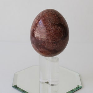 Vintage Brown Marble Stone Egg And Stand With Mirror.
Brown Marble Egg and Lucite Stand and 4-Inch Octagon Mirror. 
The Egg Has a Smooth, High Polish Finish.
The Stand is Clear Lucite.
Egg and Stand Measure 4 Inches.
The Gemstone Egg is 2 3/4 Inches by 2 Inches.
One More Really Nice Egg For your Collection.